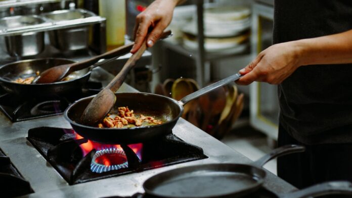 vaga-em-paciencia-para-cozinheiro Foto de cozinheiro preparando pratos em uma empresa de grande porte em Paciência.